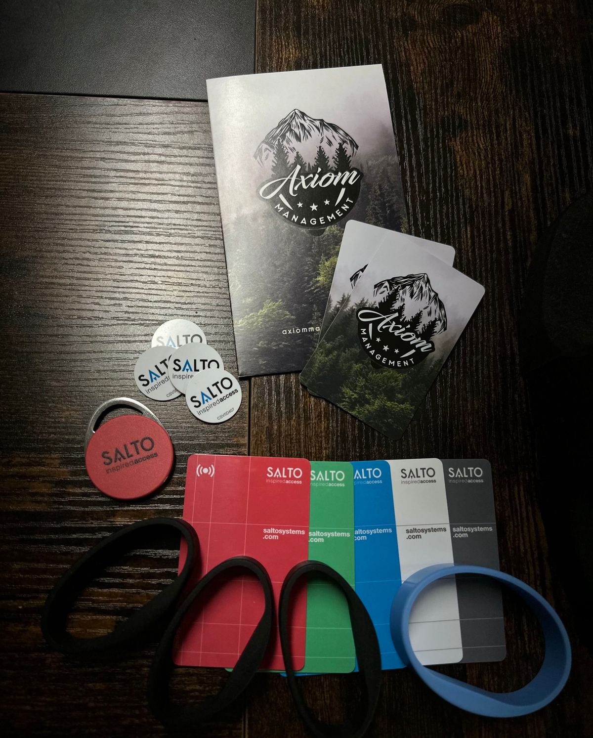 Axiom-branded SALTO key cards, fobs, and wristbands laid out on a table